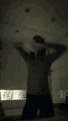 a woman in a leopard print shirt stretches her arms in a dark bathroom