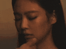 a close up of a woman 's face with her hand on her face .
