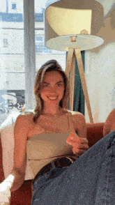 a woman is sitting on a couch with her legs crossed and a lamp in the background