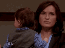 a woman is holding a small child with a nbc logo on her shirt