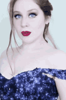 a woman in a blue off the shoulder dress with red lips