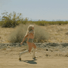a woman in a swimsuit and white boots is running in the dirt