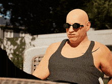 a bald man wearing sunglasses and a black tank top sits in a chair
