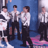 a group of young men are singing into microphones in a room