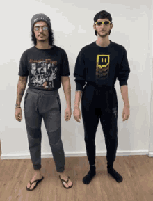 a man wearing a rolling stones shirt stands next to another man wearing a twitch sweatshirt