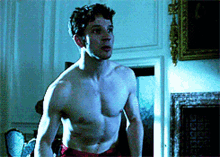 a man without a shirt is standing in a dark room