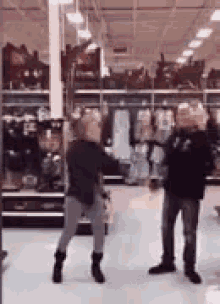 a woman is dancing in a store with a man standing behind her .