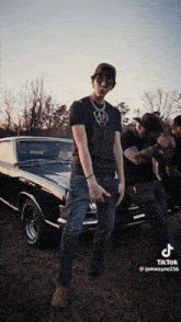 a man is standing in front of a black car with a tiktok link