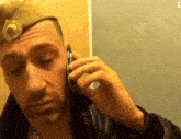 a man wearing a military hat is talking on his cell phone