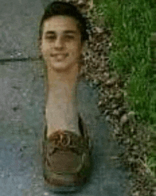 a man is standing on a sidewalk with his head in a shoe .