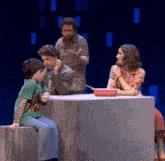 a group of people are sitting around a table with a red pan on it