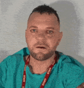 a man with a beard and a lanyard that says staff on it is making a funny face .
