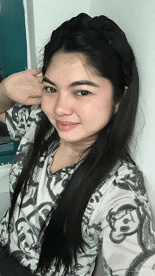 a woman wearing a headband and a shirt with monkeys on it takes a selfie