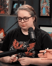 a woman wearing glasses is sitting in front of a microphone and holding a pen