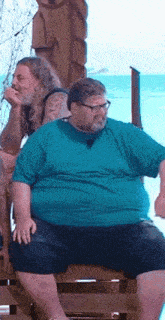 a man in a blue shirt and shorts is sitting on a wooden bench .