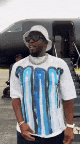 a man wearing a white hat and sunglasses is standing in front of a plane