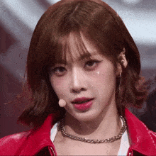 a close up of a woman wearing a red jacket and a necklace