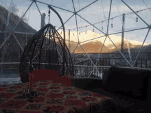 a hanging chair sits on a table with a view of a snowy mountain in the background