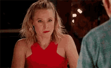 a woman in a red dress is sitting at a table with a man and looking at him .