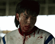 a man with blood on his face wearing a white jacket