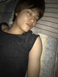 a man in a black shirt is sleeping on a striped pillow
