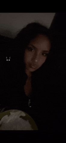 a woman is sitting in a dark room with a plate of food in front of her .