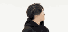 a man wearing a black hoodie is smiling and making a funny face