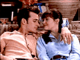 a man and a woman are sitting on a couch and the woman is wearing a blue shirt
