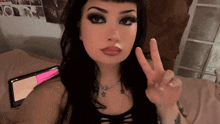 a woman is giving a peace sign in front of a tablet