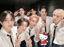 a group of young men posing for a picture with a hello kitty in the background