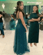 a girl in a green dress is standing next to another girl in a black dress