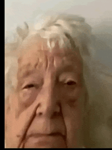 a close up of an elderly woman 's face with a very sad look on her face .