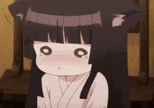 a girl with black hair and cat ears is sitting on a chair .
