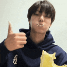 a man wearing a blue hoodie with the letter b on it giving a thumbs up