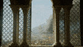 a window with columns and a view of a city with smoke coming out of it