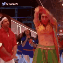 a woman in a green skirt is dancing with a man in a red shirt in the background .