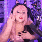a woman with pink hair wearing a cat ear headband