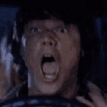 a man is driving a car with his mouth wide open