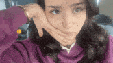 a woman in a purple sweatshirt is covering her mouth with her hands