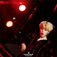 a man in a plaid shirt is singing into a microphone on stage