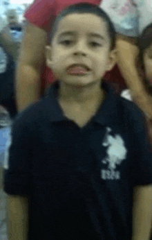 a young boy wearing a polo shirt with the word uspa on it is making a funny face .