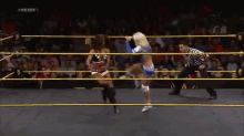 two women are wrestling in a wrestling ring with a referee and a sign that says ' wwenxt ' on it