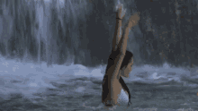 a woman in a bikini is swimming in a pool near a waterfall .