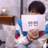 a person is holding a sign in front of their face that says ' a ' on it .