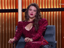 a woman in a red dress is sitting in a chair with a red bag .