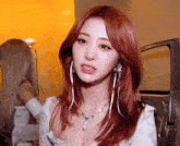 a woman with red hair is wearing a pearl necklace and earrings