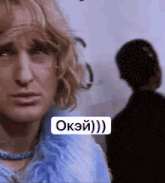 a woman in a blue fur coat is looking at the camera with a sign that says okei ) ) )