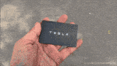 a person is holding a black tesla card