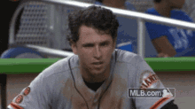 a man in a giants jersey sits in a dugout