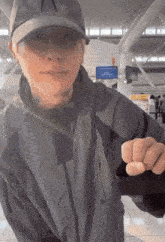 a man wearing a hat and a jacket is pointing his finger at the camera